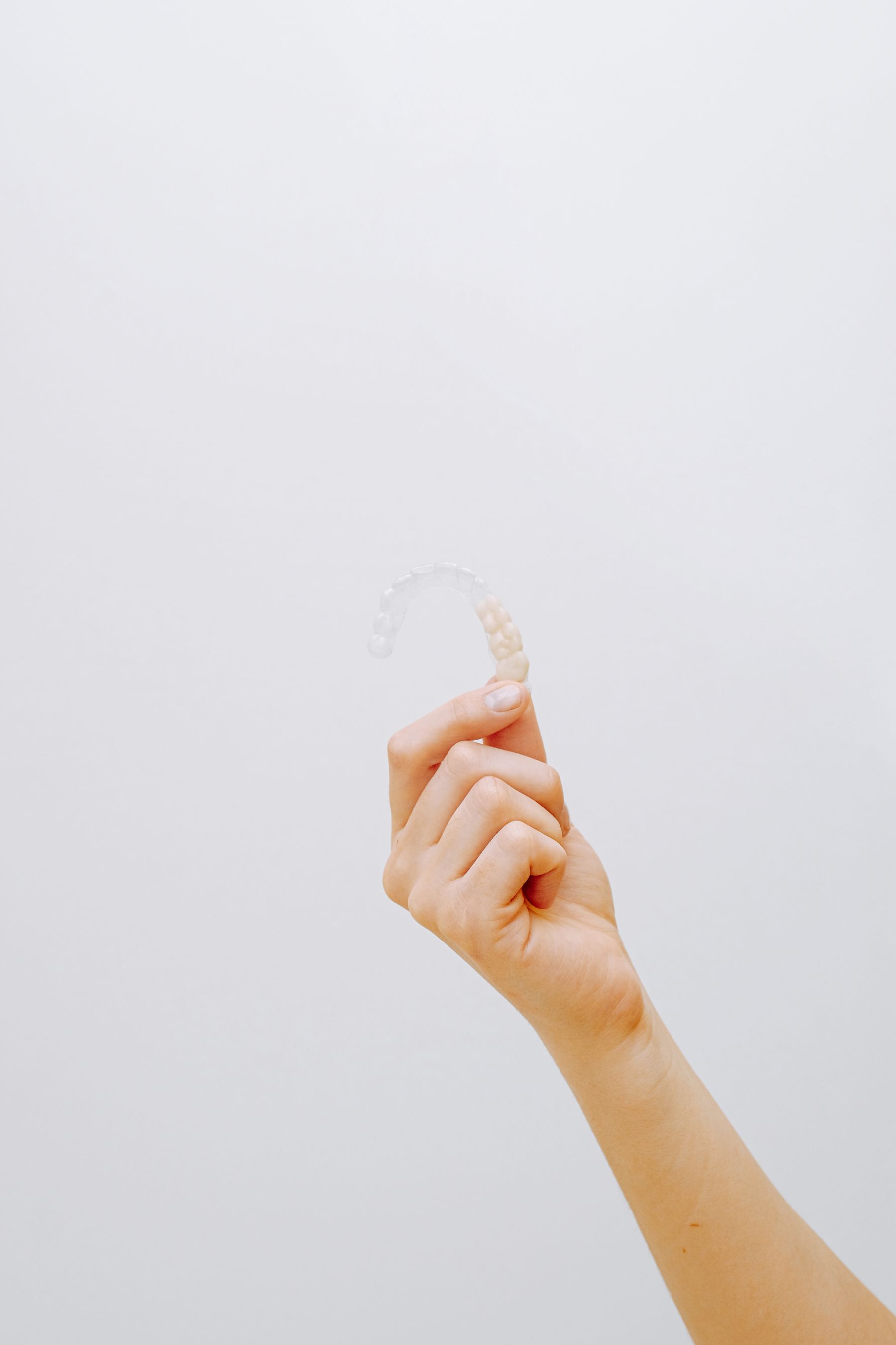A clear orthodontic aligner held up in a dental clinic