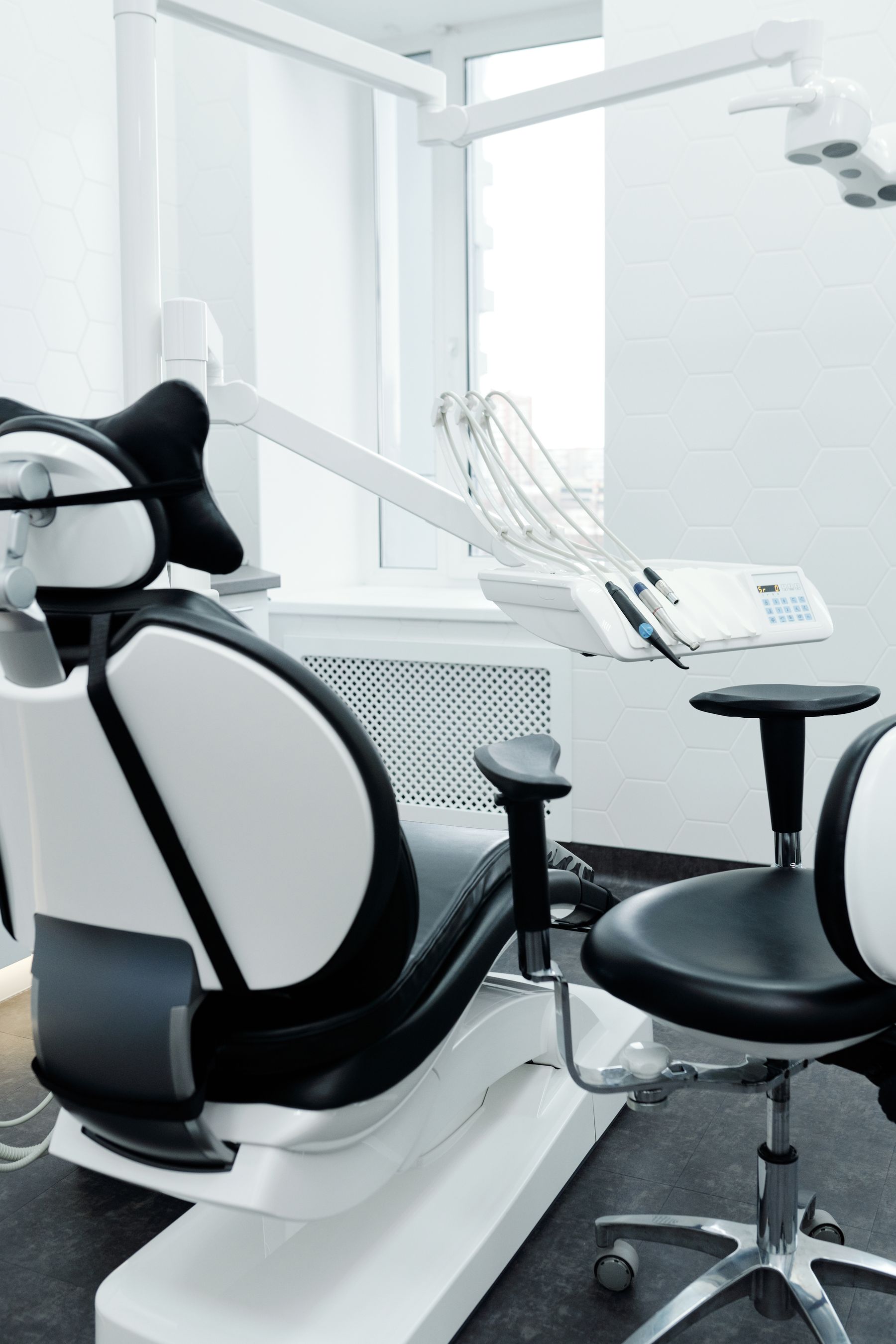 A modern dental treatment room with chair, operating light and instrument console